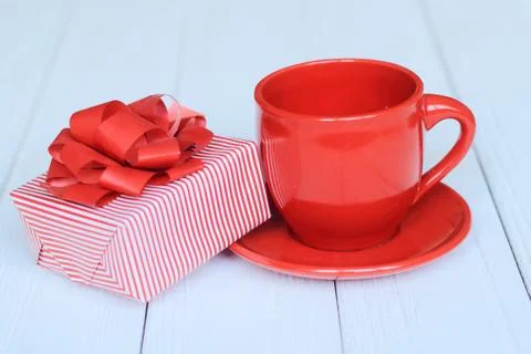Gift box and red Cup on a light wooden background Stock Photos