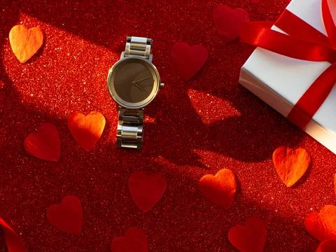Gift box and silver watch is on red heart paper background Stock Photos