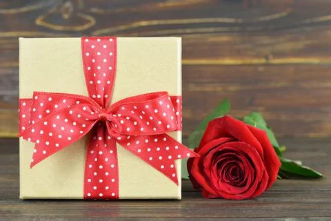 Gift box and single red rose on wooden background Foto stock