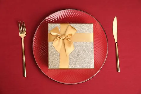Gift box and tableware on red table, flat lay. Table setting for romantic d.. Stock Photos