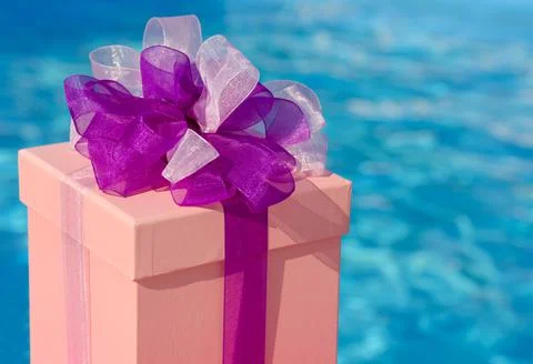 Gift box on the background of a blue pool. Stock Photos