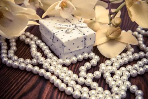 Gift box on a background of yellow orchids and pearls 스톡 사진