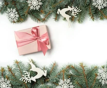 A gift box between two rows of Christmas tree branches decorated with snowfla Stock Photos