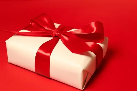 A gift box with big red bow against red background. Holidays concept Stock Photos