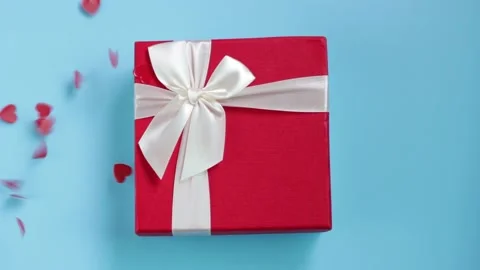 Gift box on a blue background and confetti in the shape of heart. Stock Footage 139080944