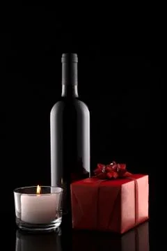 Gift box, bottle of wine, candle on black background. Stock Photos