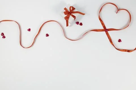 Gift box with bow and lined heart with red ribbon and hearts. Composition for Stock Photos