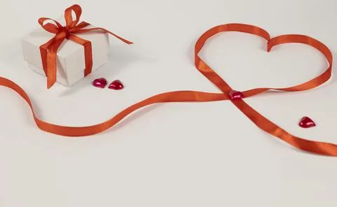 Gift box with bow and lined heart with red ribbon and hearts. Composition for Stock Photos