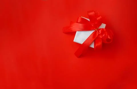 Gift box with bow on a red background Stock Photos