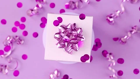 Gift box with a bow rotates on a pink background, sparkles of festive confetti Stock Footage 217678041