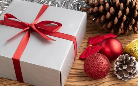 Gift box, christmas balls and bow over wooden table Stock Photos