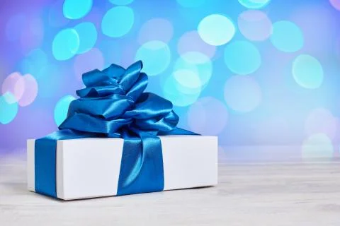 Gift box with a classic blue bow on a background with bokeh defocus backgroun Stock Photos