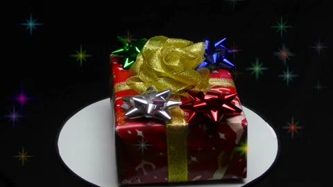 Gift box in colored packaging rotates on a black background with colorful lights 스톡 동영상 165090185