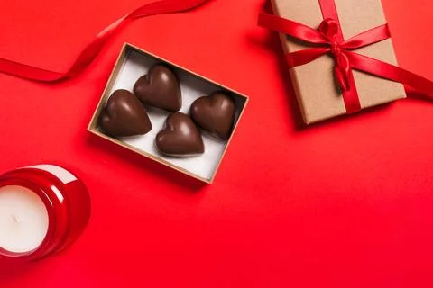 A gift box containing heart-shaped chocolates decorated with a red ribbon o.. Stock Photos