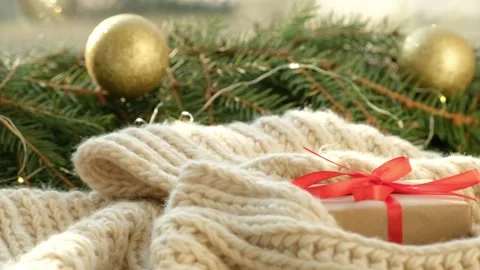 Gift box on cozy scarf close up. Christmas background, present with red ribbon Stock Footage 163885292