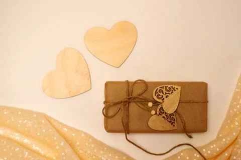 Gift box in craft paper on a light background, wooden hearts Foto stock