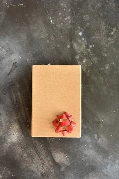 Gift box on a dark background, decorated with a textured bow. Stock Photos