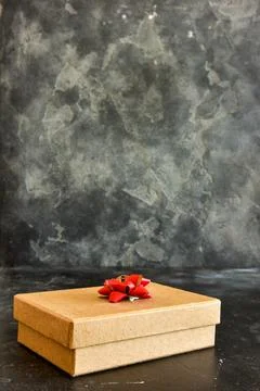 Gift box on a dark background, decorated with a textured bow. Stock Photos