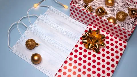 Gift box decorated with a bow with balls and a mask on a blue background. Top Stock Photos