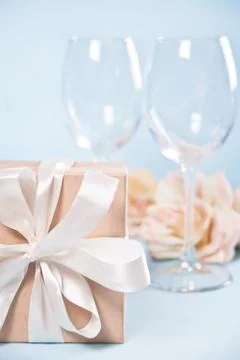 Gift box with empty two wineglasses and flowers on the background. Romantic d Stock Photos