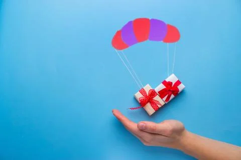 Gift box falling down with parachute Stock Photos