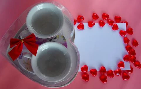 Gift in a box in the form of a heart, two tea mugs on a pink background. Tea Stock Photos