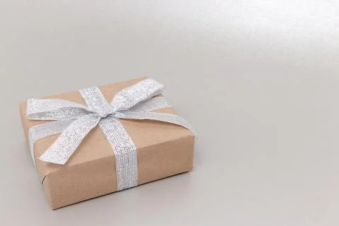 Gift box in front of silver colored background. Stock Photos