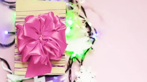 Gift box with a large pink bow on a pink background with a garland. Stock Footage 142358967