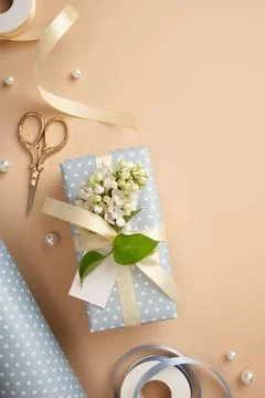 Gift box in light blue polka dot paper with cream satin ribbon, white lilac f 库存照片