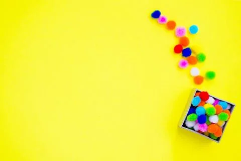 Gift box with multi-colored confetti on a yellow background. Stock Photos