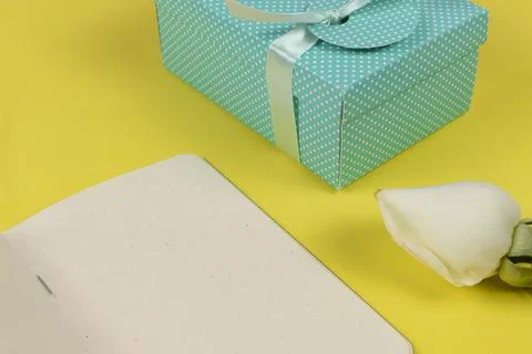 Gift box next to notepad and a flower Stock Photos