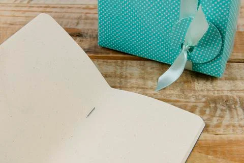 Gift box next to paper notepad on rustic wooden background Foto stock