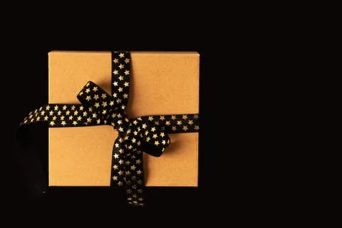 Gift box or present box with black golden ribbon on black background. Foto stock
