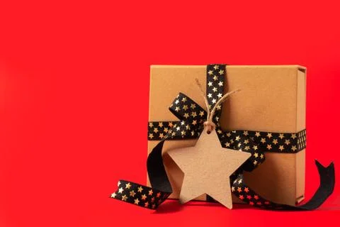 Gift box or present box with empty mock up tag, black golden ribbon on red ba Stock Photos
