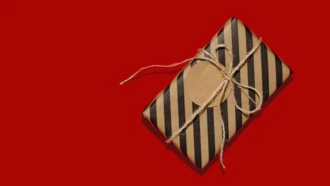 Gift box or present wrapped in craft paper with tag or label. Stock Photos