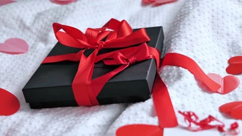 Gift box packed and postcard decorated with a red beautiful bow on the bed. Vale Stock Footage 169518539