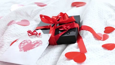Gift box packed and postcard decorated with a red beautiful bow on the bed. Vale Stock Footage 169520359