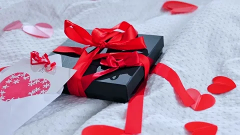 Gift box packed and postcard decorated with a red beautiful bow on the bed. Vale Stock Footage 169520495