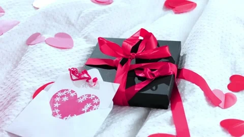 Gift box packed and postcard decorated with a red beautiful bow on the bed. Vale Stock Footage 169520699