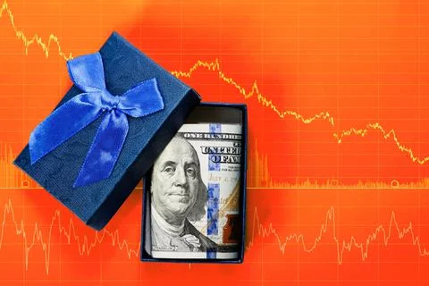 Gift box with packed dollars. On red background is diagram of stock trading a Stock Photos