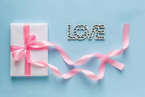 Gift Box is packed into simple white parir with pink ribbon and woode word lo Stock Photos