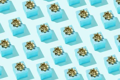 Gift box pattern with golden bow on the pastel blue background Stock Photos