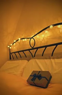 Gift box placed on comfortable bed with romantic atmosphere Stock Photos