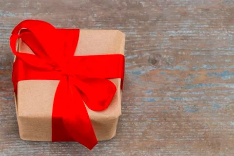 Gift box present with red bow ribbon and brown krafts wrapping paper on  wood Stock Photos