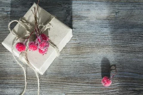A gift box with red berries, packed in kraft paper and tied with linen twine  Foto stock
