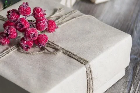 A gift box with red berries, packed in kraft paper and tied with linen twine  Stock Photos