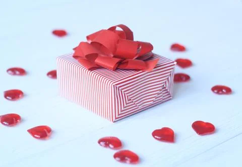 Gift box with red bow and hearts on light background Stock Photos