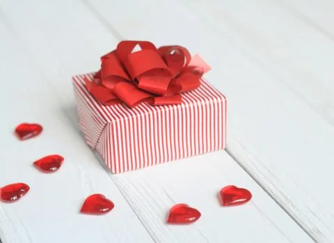 Gift box with red bow and hearts on light background Foto stock