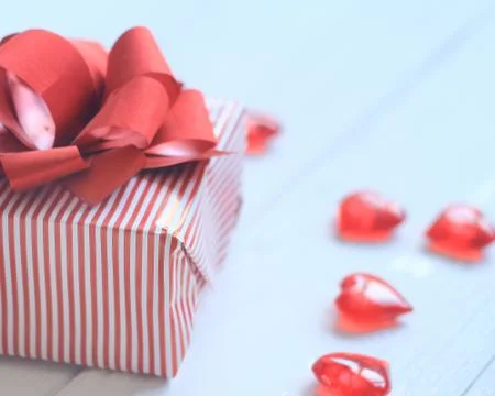 Gift box with red bow and hearts on light background Stock Photos