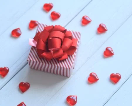 Gift box with red bow and hearts on light background Foto stock